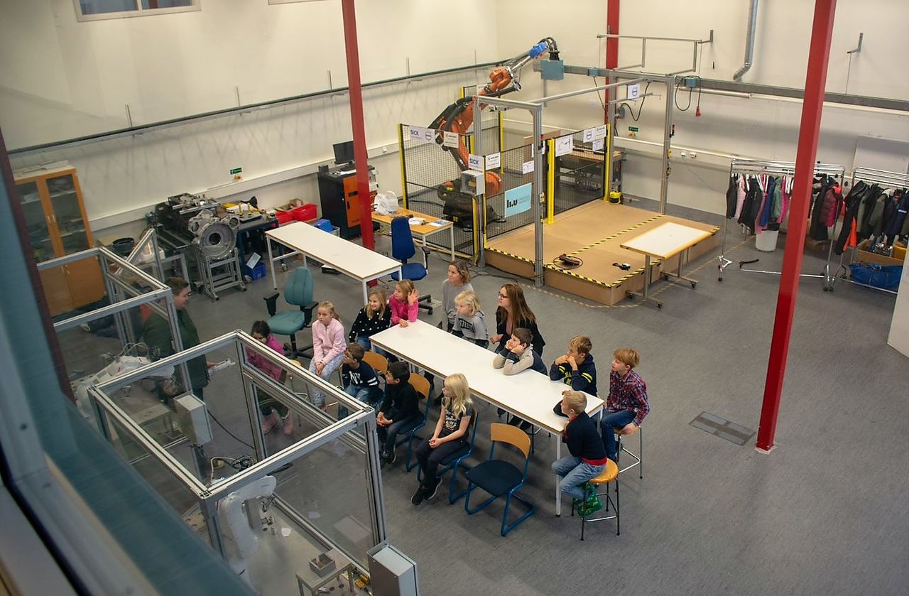 man visar skolbarn robot