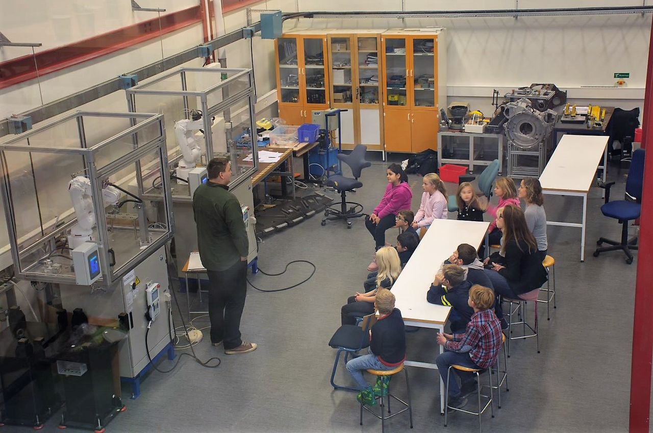 man visar skolbarn robot