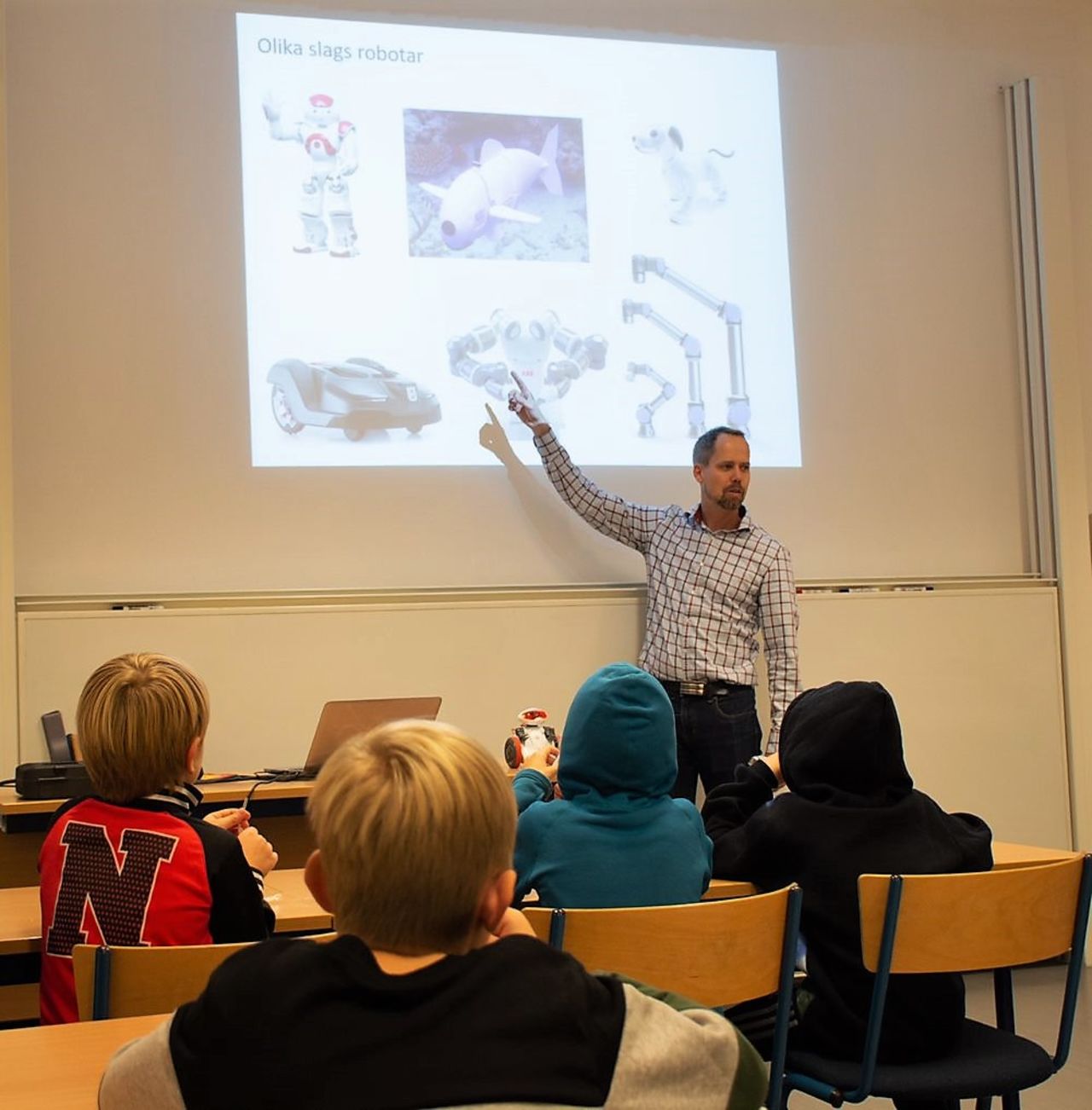 man visar skolbarn robot