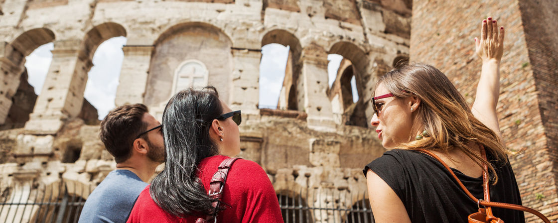 Turister med guide framför Colosseum i Rom.