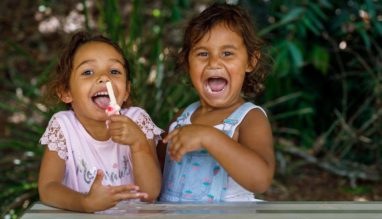 Two Young Australian Aboriginal Girls eating an Ice Cream at park at Lismore, NSW, Australia