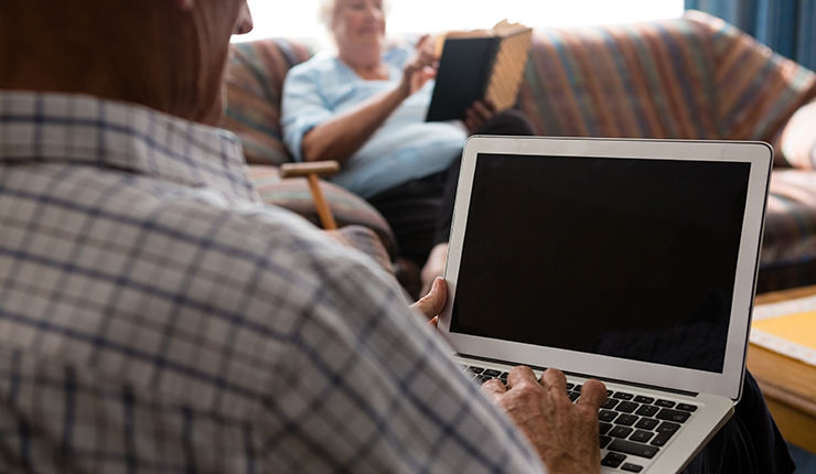 Side view of senior man uisng laptop in nursing home