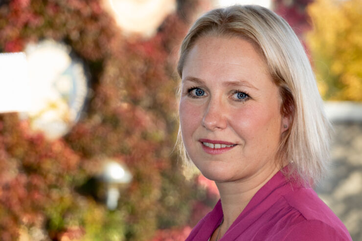 Portrait of a blonde woman in cerise blouse in front of a window