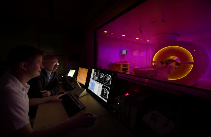 Two scientists are sitting infront of an MRI