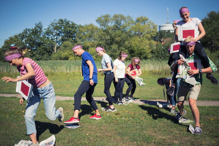 Studenter som leker en stafettlek med tidningar