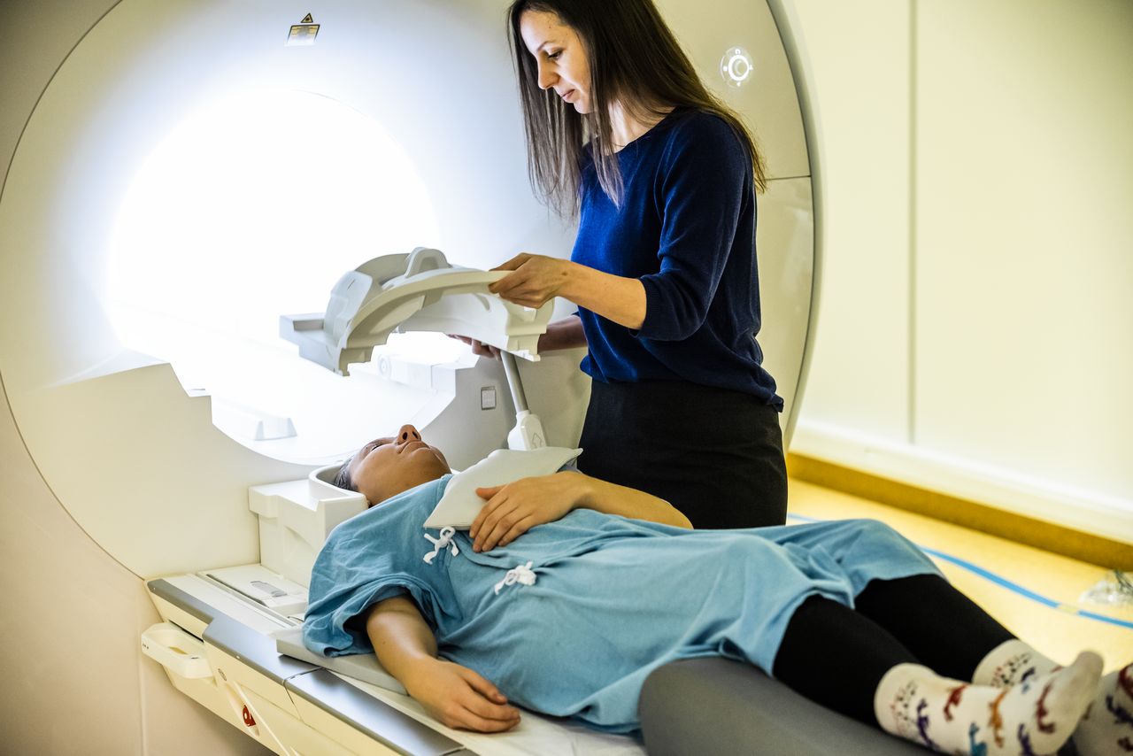 A researcher is assisting a test subject before an MRI scan.