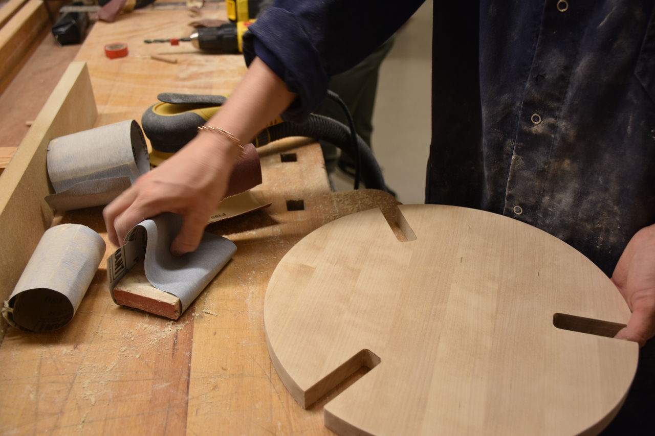 En hand som sträcker sig efter sandpapper att använda på en pall under konstruktion