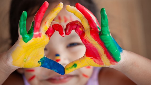 Barn med målande fingrar gör hjärta med fingrarna.