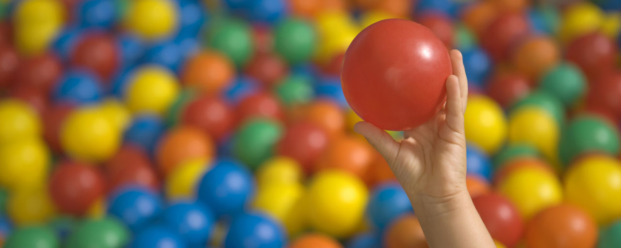 Barns hand håller en boll i ett bollhav