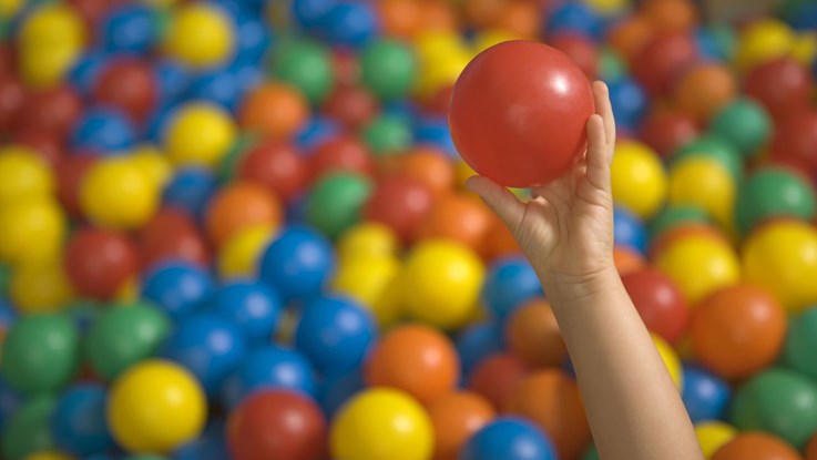 Close-up of a child's hand holding a ball in a ball pool