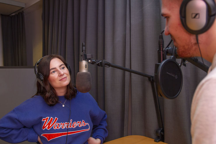 Two students at the microphones in a sound studio.