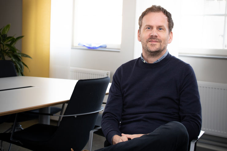 Man sitting by a conference table, looking in to the camera