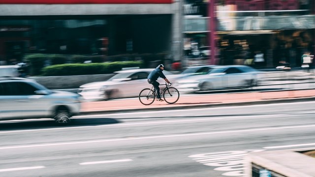 A man bikes among cars