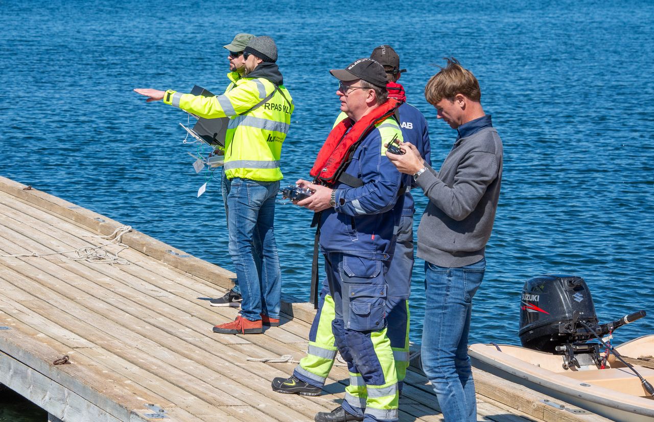 Människor stående på en brygga, några av dem håller i radiokontroller.