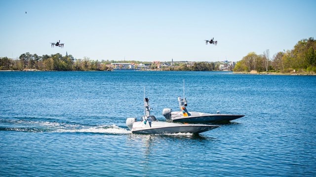 Two boats in the water, two drones in the air above them