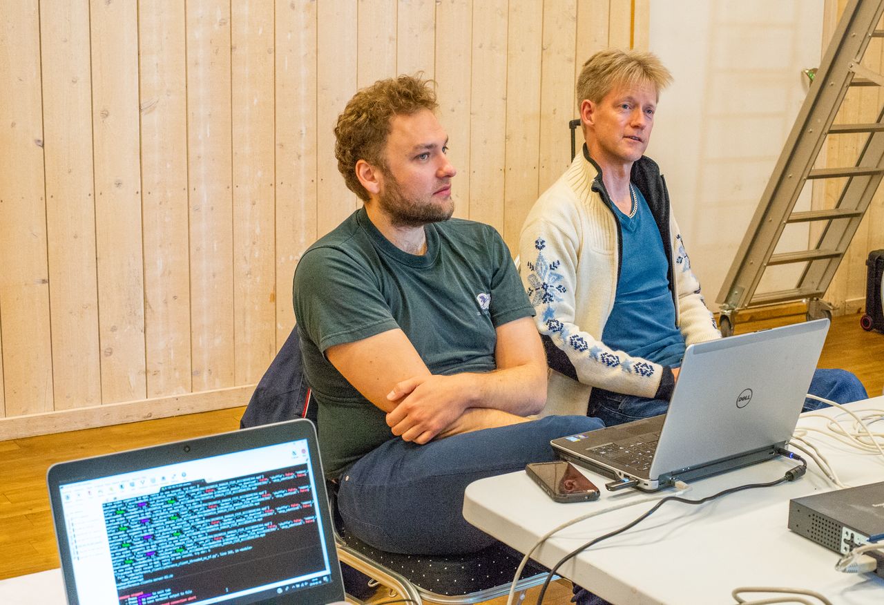 Två män sitter framför en laptop.