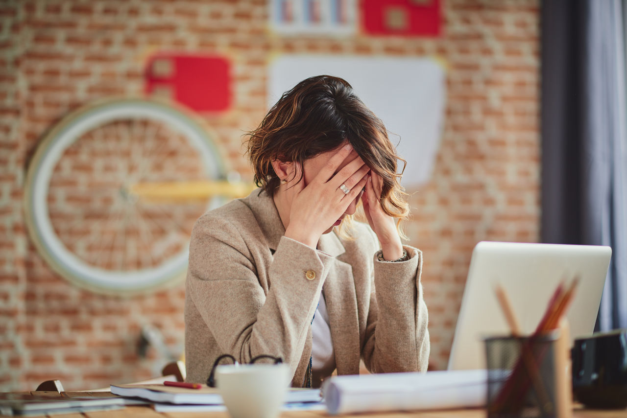 Woman at computer leaning head in hands.