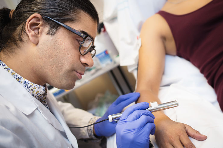 researcher applies a very thin filament to the hand to measure properties of nerve cells in the skin