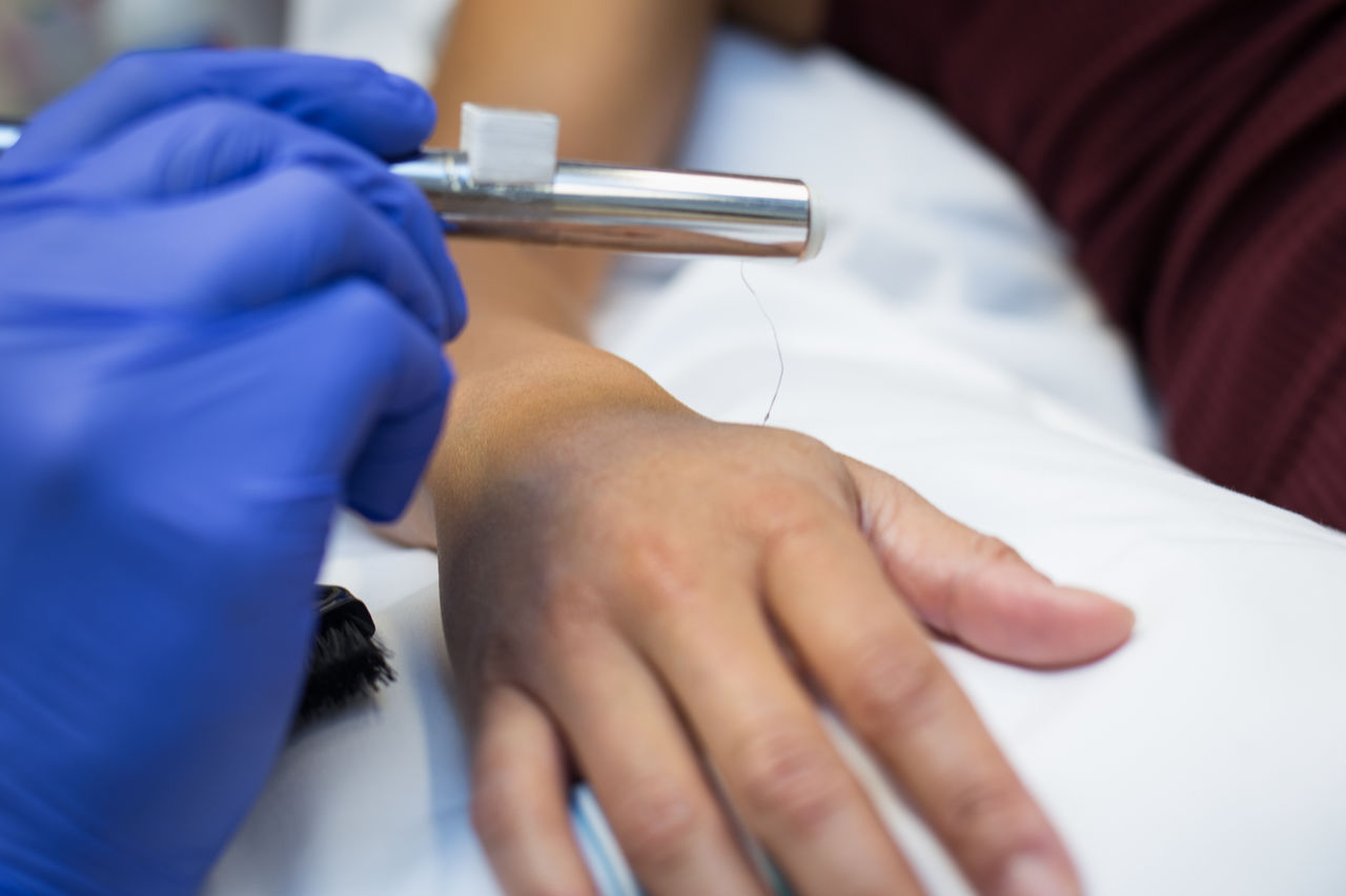 researcher applies a very thin filament to the hand to measure properties of nerve cells in the skin