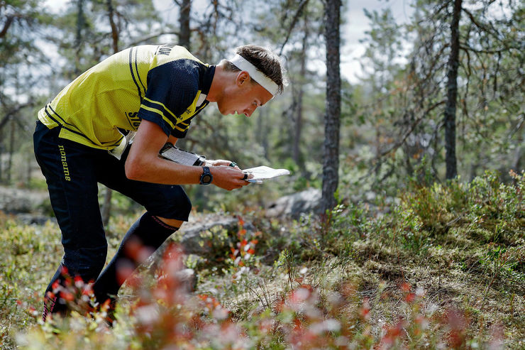 En man i träningskläder orienterar i en skog.
