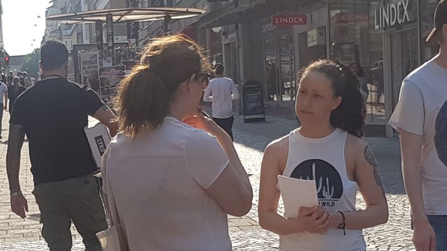 Ung kvinna ställer fråga till annan kvinna i stadsmiljö.