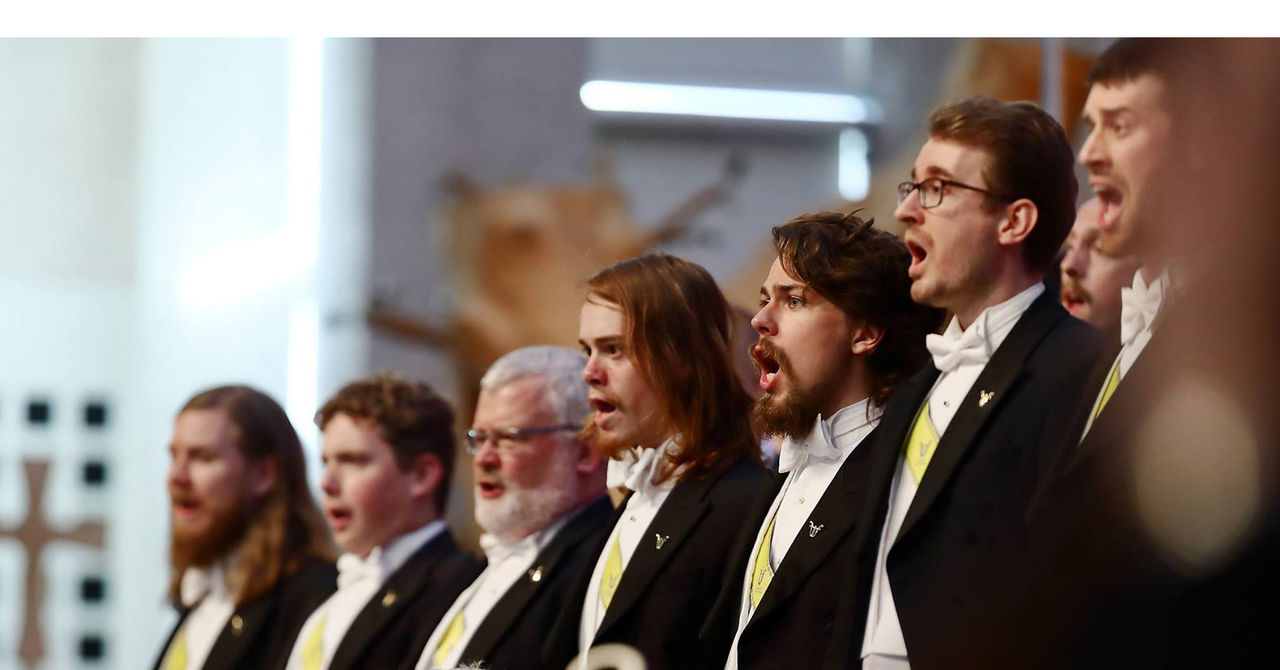 Korister ur kören sjunger under en konsert.