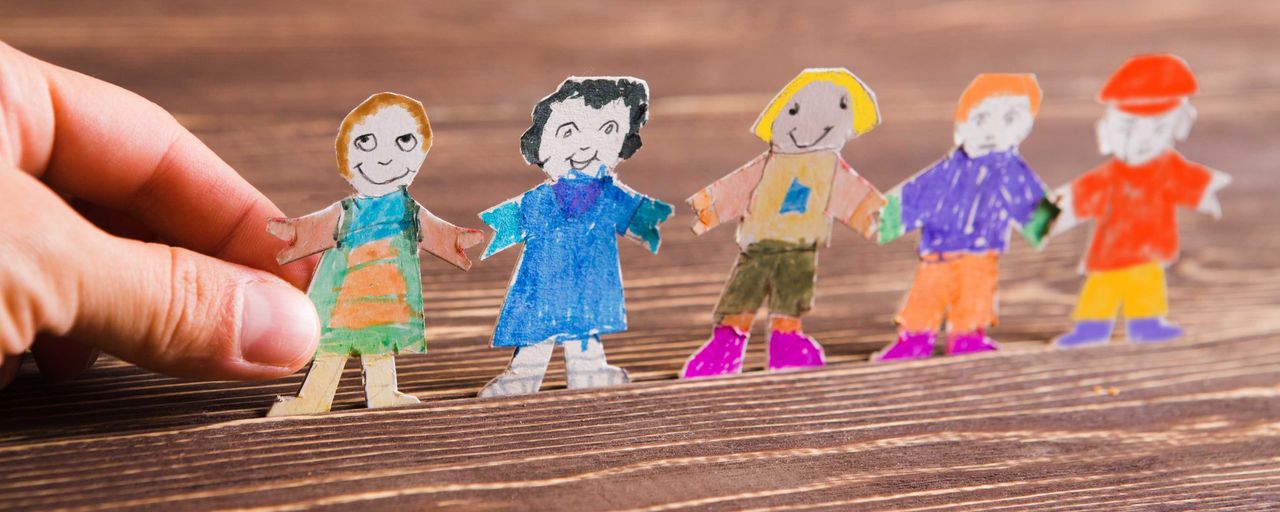 Barn gör pappersfigurer på träbakgrund.