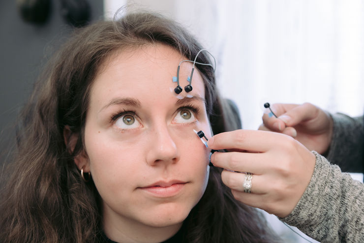 forskare fäster elektroder på en ung kvinnas ansikte