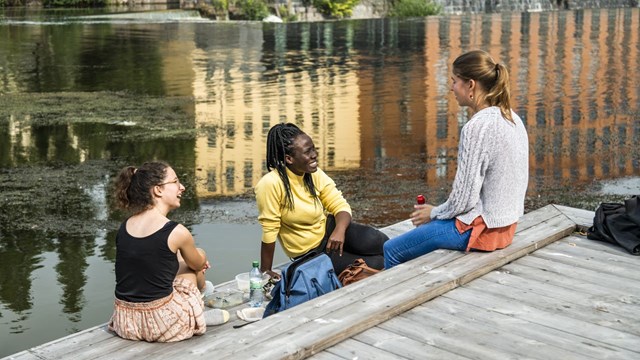 Tre kvinnliga studenter som sitter vid Strömmen i Norrköping