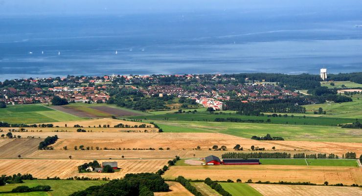 Landskap med hus, vidder och himmel.