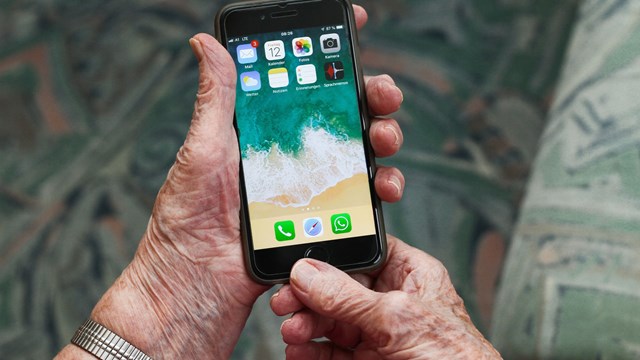 Bild på äldre persons händer som håller en Iphone