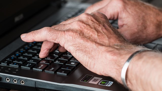 Bild på äldre händer som skriver på ett tangentbord