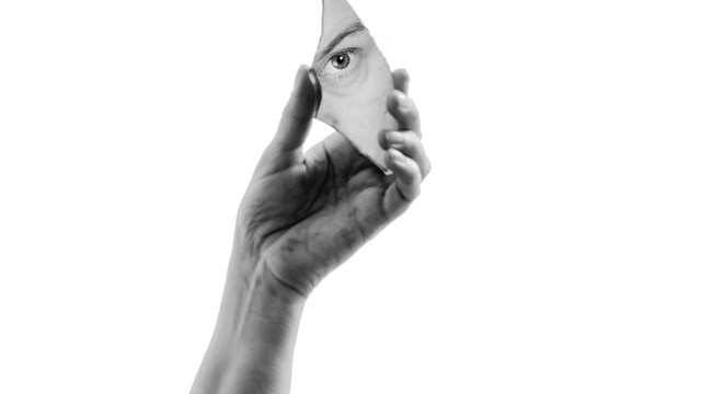 Hand som håller en spegel som visar ett öga