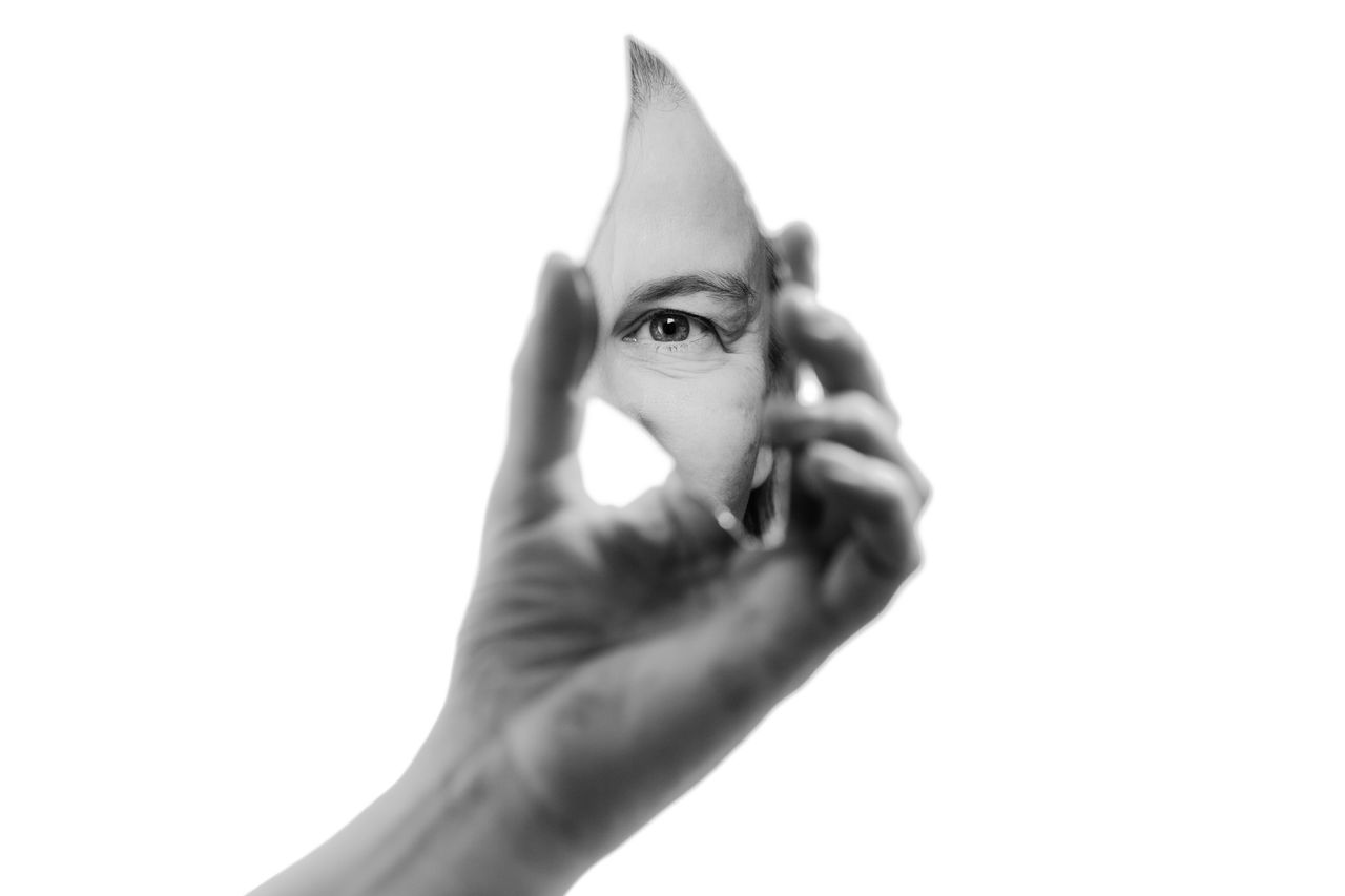 Hand som håller i en spegelskärva som visar ett öga