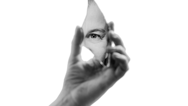 Hand som håller i en spegelskärva som visar ett öga