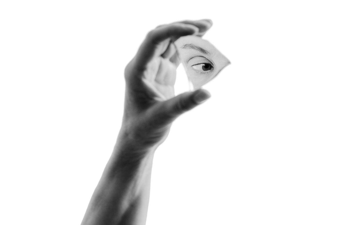 Hand som håller en spegelskärva som visar ett öga