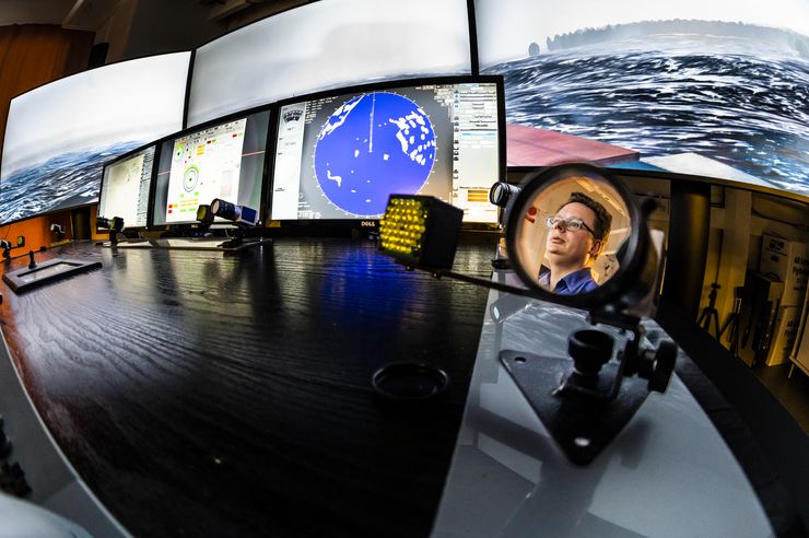 Screens showing a simulation, the person in charge of the simulation is shown in a mirror in front of the screens