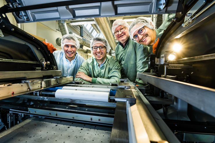 Four men wearing hair nets photographed through a machine that gives the picture a nice frame.