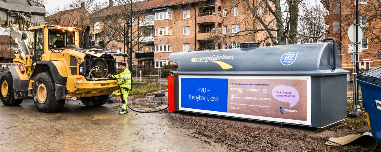 En man fyller bränsle i ett arbetsfordon från en stor tank