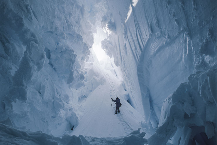 Inne i isen. Blå is och snö, en person står i bakgrunden.