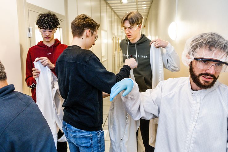 High school students putting on protective lab coats.