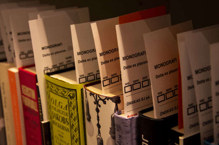 A shelf with books with paper slips.