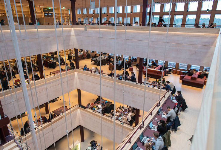 Four floors in a large building. At every floor, there are people sitting reading and using computers.