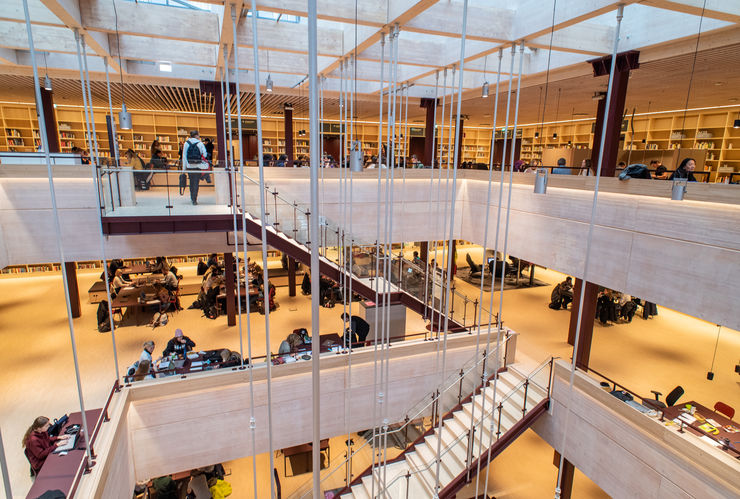 A wooden staircase in a large building connecting several floors.