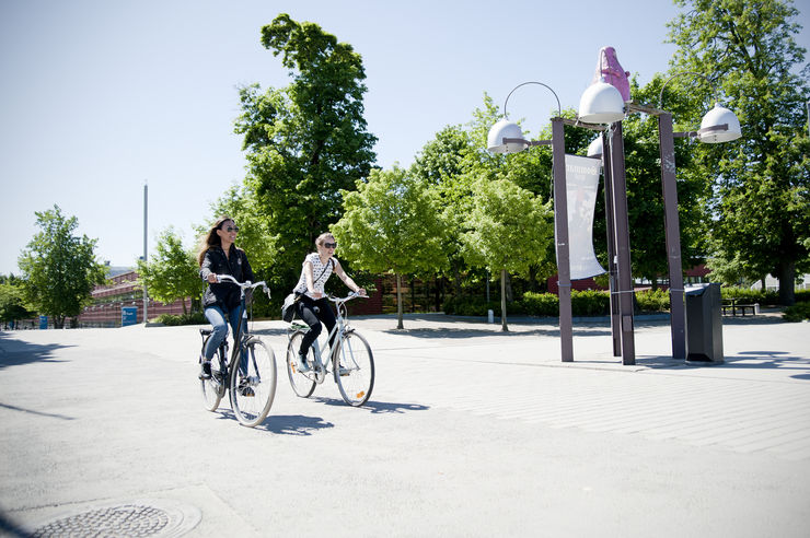 Två kvinnliga studenter som cyklar på Campus Valla i Linköping.