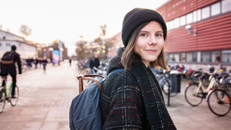 Kvinnlig student med ryggsäck utanför hus på Campus Valla i Linköping.