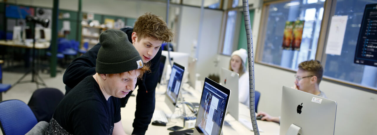 Studenter i sal för programmering, Fascinerade ansiktsuttryck när de betraktar skärmarna.