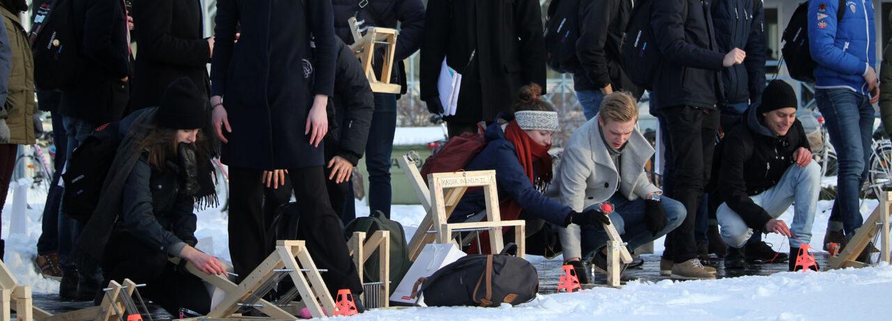  Studenter och mekaniska träapparater uppradade framför snötäcke