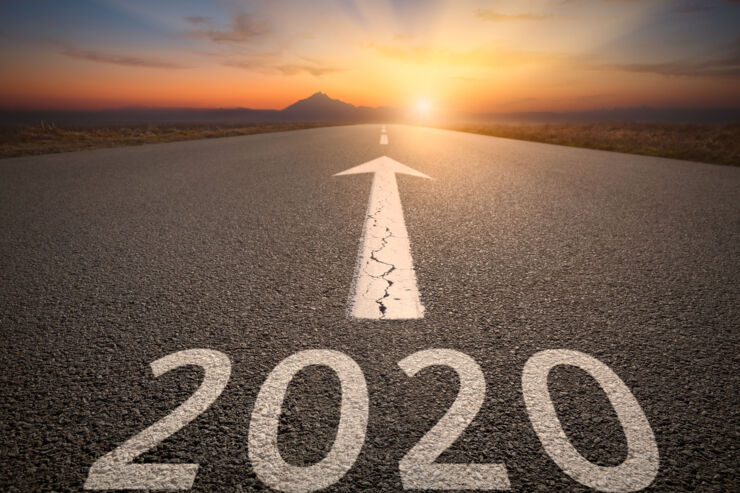 A road leading to a sunset. 2020 is written on the road with white paint, above it an arrow is pointing in the direction of the horizon.