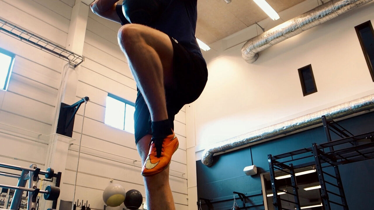 Man som gör höga knälyft på gym.